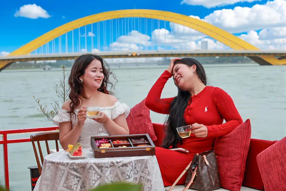 Two Women Enjoying High Tea Afternoon In Front Of Nguyen Hoang Bridge